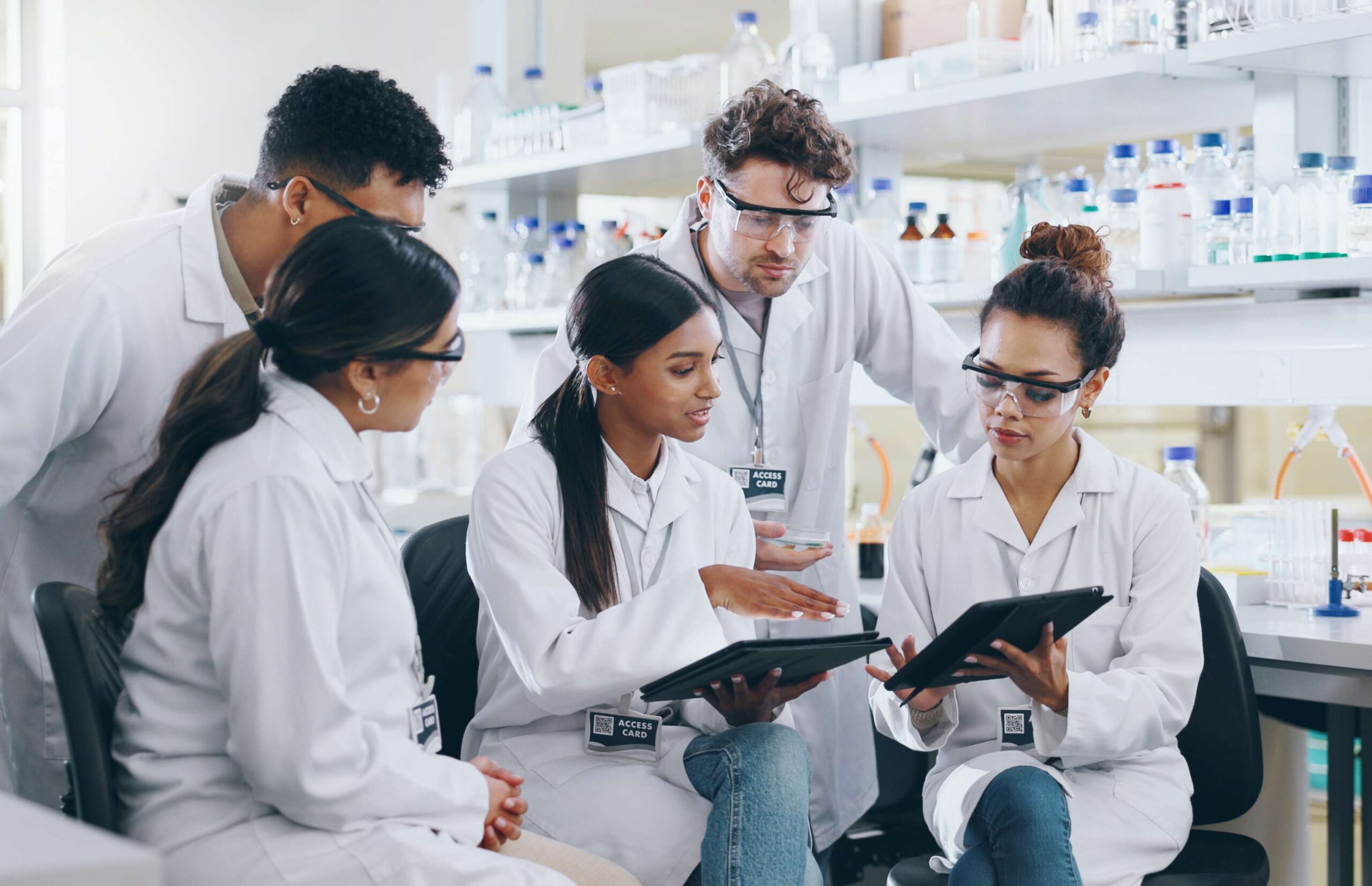 Tablet, science team and people learning for cancer cure, help or medical development in laboratory. Training, investigation or research info with scientists in clinical trial for medicine internship.
